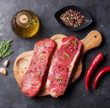 Two NY strip steaks seasoned on a board
